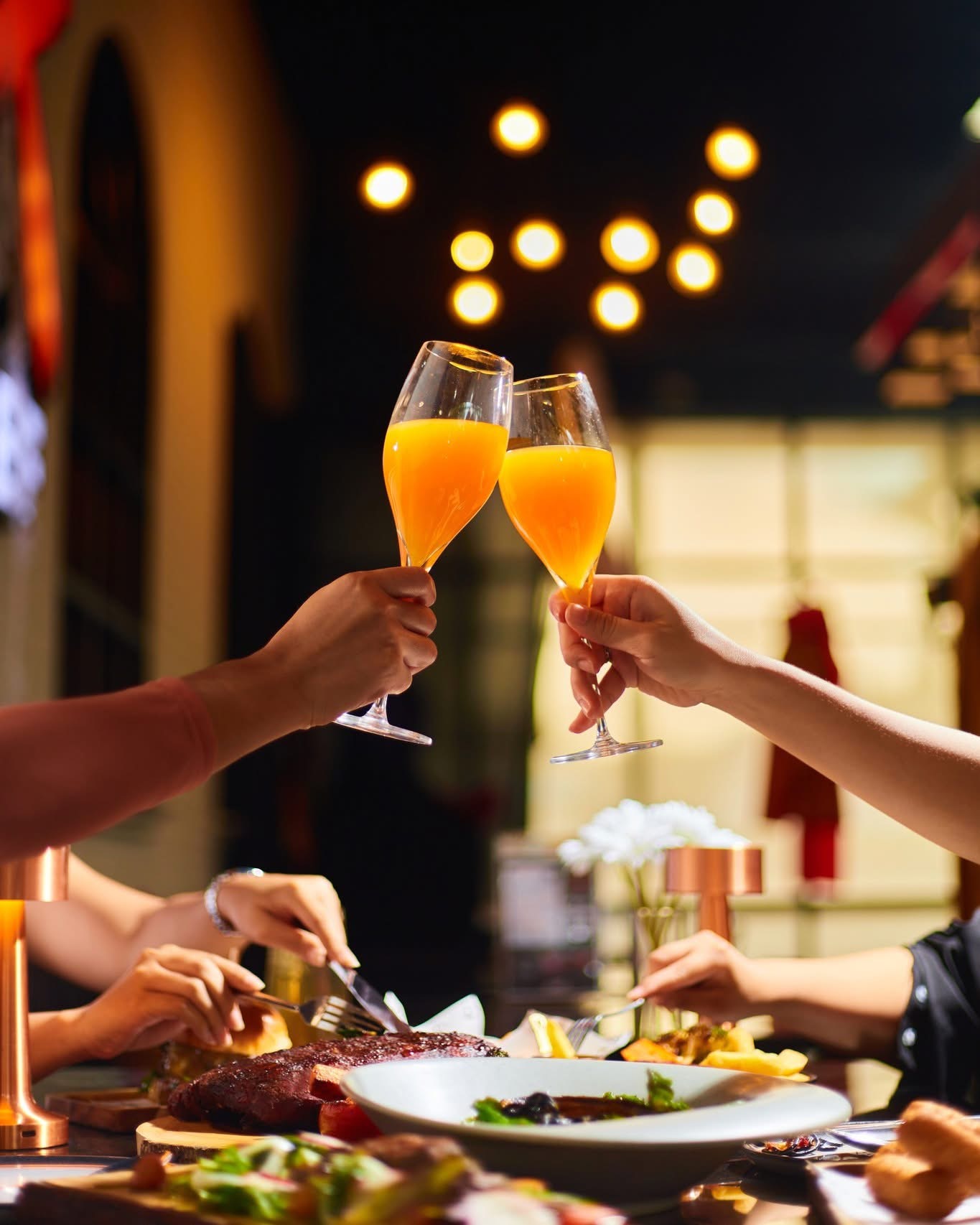 Guests raising drinks over dinner at X BEEF